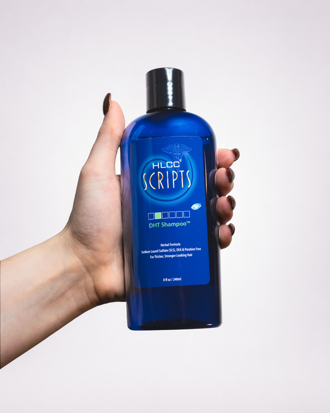 Hand holding HLCC Scripts DHT Shampoo bottle