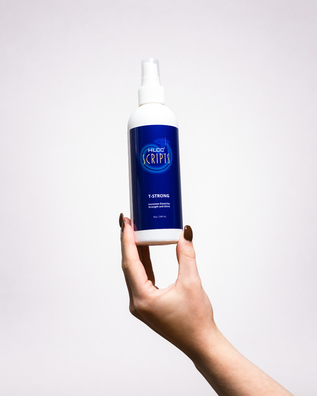 Hand holding HLCC Scripts T-Strong spray bottle